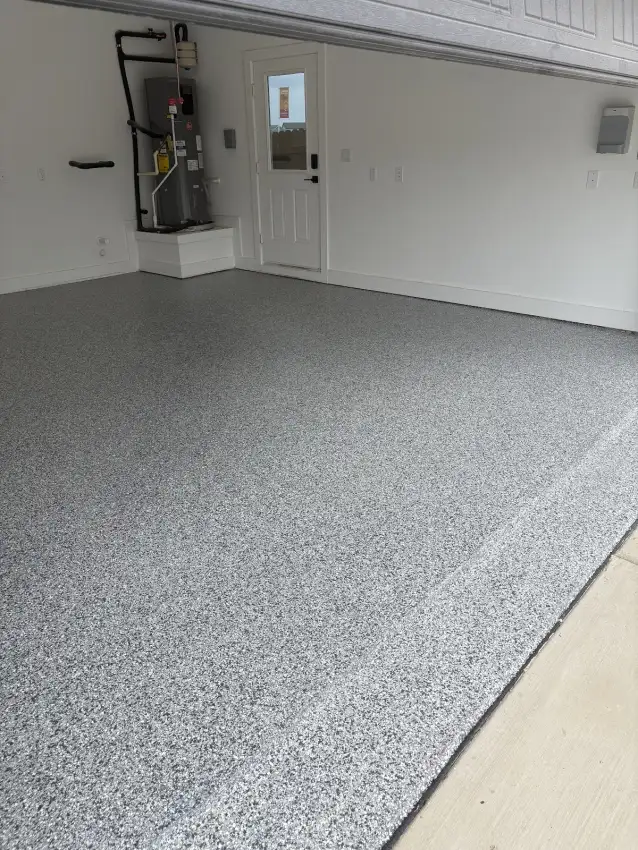 Finished gray flake garage floor beside a utility wall
